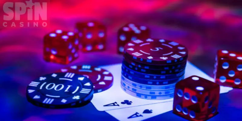 Cartas y dados sobre una mesa con logo de spin casino al lado izquierda superior