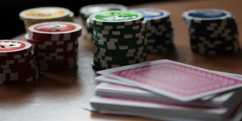 mesa con un montón de cartas y varios montones de fichas de póker de varios colores