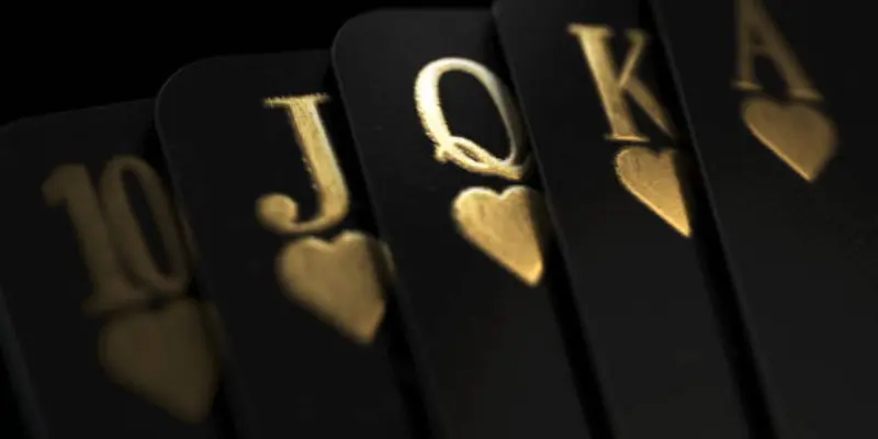 quina de cartas de póker negras con letras doradas